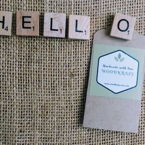 May include: Wooden letter tiles spelling "HELLO" on a burlap background with a brown paper tag that says "Handmade with love WOODKRAZY www.woodkrazy.etsy.com"