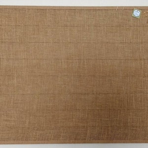 May include: A brown cork board with a textured surface. Two small white tags are pinned to the board.