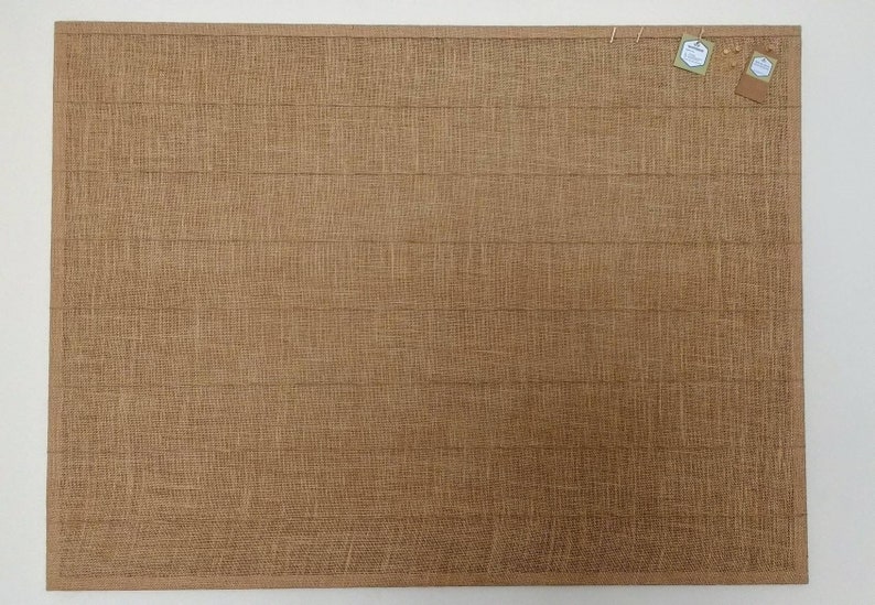 May include: A brown cork board with a textured surface. Two small white tags are pinned to the board.