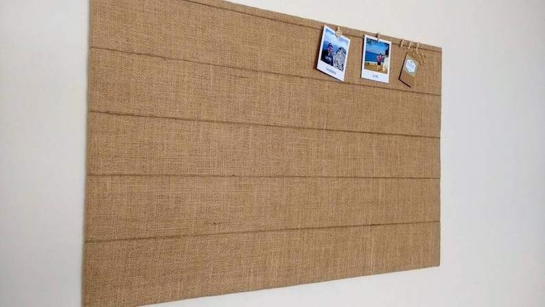 Fabric notice board covered in natural hessian with strings.