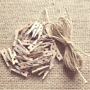 May include: A pile of wooden clothes pegs with metal springs, and a ball of twine on a hessian background.