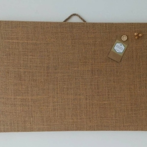 May include: A brown burlap cork board with a small, white label that says "Handmade with Love" and a few wooden push pins.