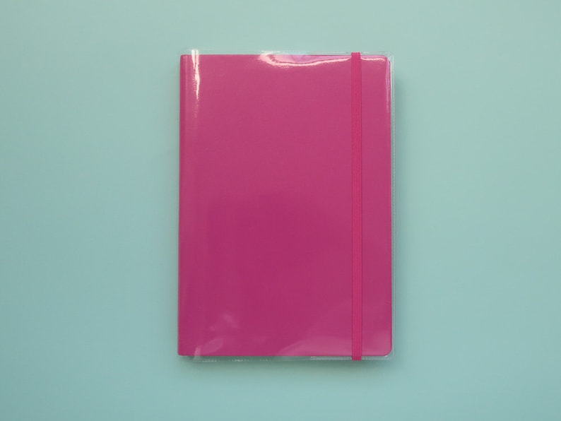 May include: A pink notebook with a pink elastic closure.