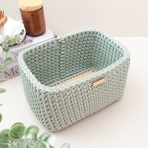 Könnte beinhalten: Ein grüner, gehäkelter Aufbewahrungskorb mit einem Holzschild, auf dem "The Home Edit" steht.