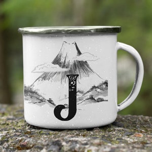 May include: White enamel mug with a black and white illustration of a mountain and the letter "J" on it.