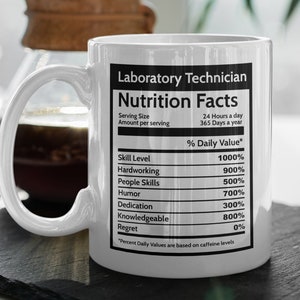 Può includere: Una tazza in ceramica bianca con una grafica in bianco e nero di un'etichetta di informazioni nutrizionali per un tecnico di laboratorio. L'etichetta elenca le competenze e il loro valore giornaliero percentuale, come il livello di competenza 1000%, il lavoro duro 900%, le capacità interpersonali 500%, l'umorismo 700%, la dedizione 300%, la conoscenza 800% e il rimpianto 0%.