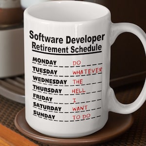 May include: White ceramic coffee mug with a black and red design. The mug reads "Software Developer Retirement Schedule" and lists the days of the week with a humorous retirement schedule.