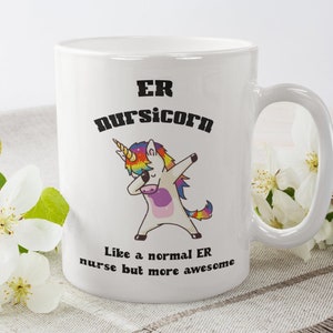 May include: White ceramic mug with a black and white illustration of a unicorn doing the dab. The text "ER Nursiicorn" is above the unicorn and the text "Like a normal ER nurse but more awesome" is below the unicorn.