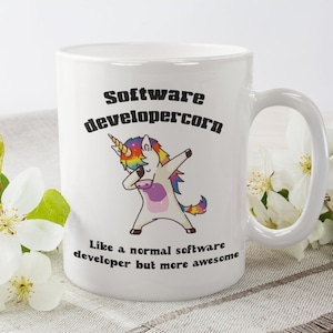 May include: White ceramic mug featuring the text "Software developercorn" and a cartoon unicorn in a dabbing pose. The unicorn has a rainbow mane and tail. The mug also has the text "Like a normal software developer but more awesome."