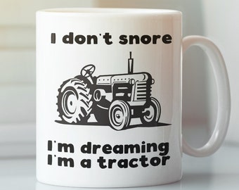 Könnte beinhalten: Weiße Keramiktasse mit einer schwarzen Traktor-Illustration und dem Text "Ich schnarche nicht, ich träume, dass ich ein Traktor bin".