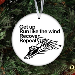 May include: White round Christmas ornament with black text and a black and white illustration of a running shoe with wings. The text reads "Get up Run like the wind Recover Repeat".
