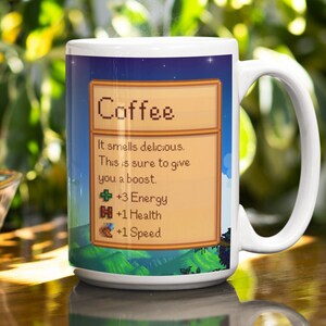 May include: White ceramic coffee mug with a pixelated design. The mug features a blue background with a green landscape and a yellow box with the text "Coffee" and a description of the coffee's effects: "It smells delicious. This is sure to give you a boost. +3 Energy +1 Health +1 Speed"