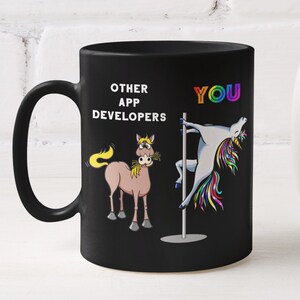 May include: Black coffee mug featuring a humorous illustration of a unicorn performing a pole dance alongside a horse. The mug's text reads "Other App Developers" and "You".