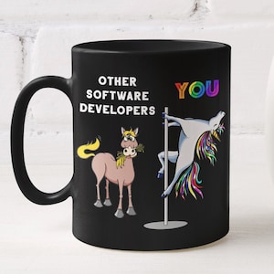 Może przedstawiać: Czarny ceramiczny kubek z napisem "OTHER SOFTWARE DEVELOPERS YOU" i rysunkiem jednorożca i konia z kreskówek. Jednorożec jest na słupie, a koń trzyma kwiaty. Po prawej stronie biały wazon z żółtymi kwiatami.