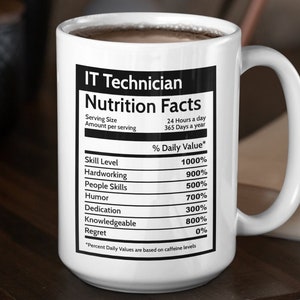 May include: White ceramic mug with a black and white graphic that reads "IT Technician Nutrition Facts" with a humorous list of skills and their percentage daily value. The mug is filled with coffee and sitting on a wooden table.