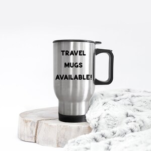 K&ouml;nnte beinhalten: Eine Reise-Thermoskanne aus Edelstahl mit schwarzem Deckel und Griff. Auf der Kanne steht der Text "TRAVEL MUGS AVAILABLE!" gedruckt.