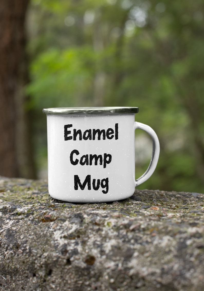K&ouml;nnte beinhalten: Wei&szlig;e Emaille-Camping-Tasse mit schwarzem Text "Enamel Camp Mug".