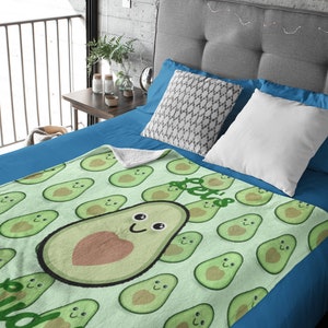 May include: A green and brown fleece blanket with a pattern of avocado halves. The avocado halves have a smiling face and a heart in the center. The text "I love avocado" is written on the blanket.