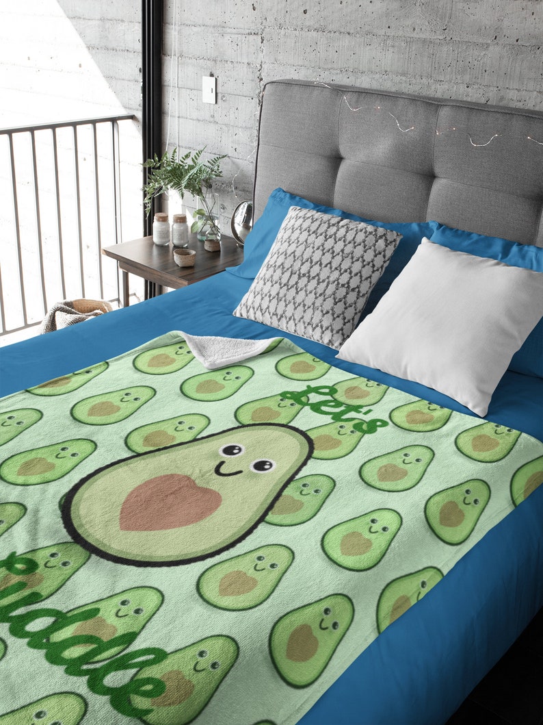 May include: A green and brown fleece blanket with a pattern of avocado halves. The avocado halves have a smiling face and a heart in the center. The text "I love avocado" is written on the blanket.