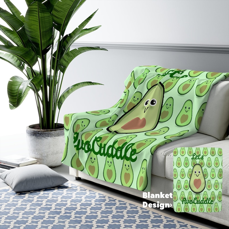 May include: A green and brown throw blanket with a repeating pattern of avocado halves with faces. The text "Let's AvoCuddle" is written in a green cursive font on the blanket.