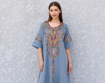 May include: A light blue, knee-length dress with short sleeves and intricate, colorful embroidery around the neckline and bodice. The dress has a relaxed fit and a subtle textured pattern. The embroidery features a variety of colors, including red, yellow, and green.