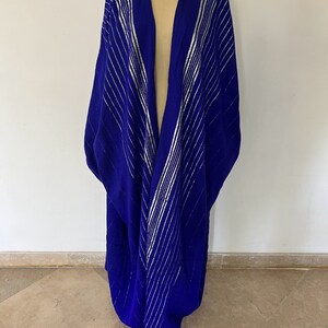 Op de afbeelding: Een koninklijk blauwe, lange, met lange mouwen, met zilveren strepen. De robe is open aan de voorkant en heeft een V-hals.