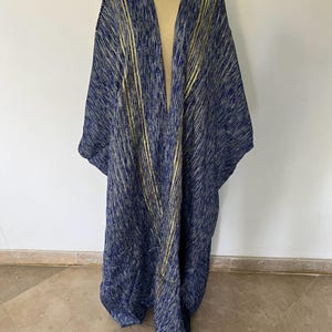 Op de afbeelding: Een lange, marineblauwe en gouden kimono met een V-hals en een losse pasvorm. De kimono heeft een textuur met gouden strepen.