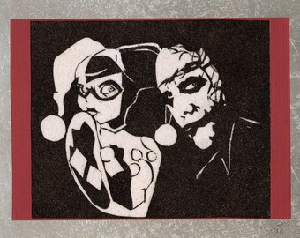 Tableau de sable naturel 18x24 cm Rencontre d’un Joker et d’une Harley Quinn au travers des années