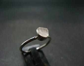 Op de afbeelding: Een zilveren ring met een heldere, gefacetteerde edelsteen in het midden.