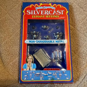 May include: A box of Terra's Treasures Silvercast Elegant Settings, a 12-piece coffee and tea service made of non-tarnishable metal. The box features a picture of a young girl holding a teacup and saucer, and the text "Terra's Treasures Silvercast Elegant Settings" is printed on the front of the box.