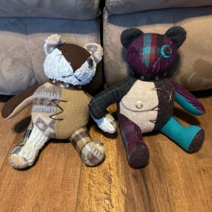 May include: Two handmade teddy bears with patchwork designs. One bear has a brown and tan color scheme with a stitched face and a small collar. The other bear features a purple, teal, and black color palette, also with a stitched face and a collar.