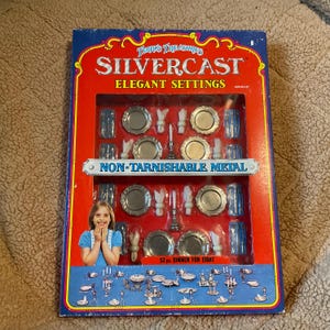 May include: A vintage Silvercast Elegant Settings 52-piece dinner set for eight. The box is red and blue with the text "Terry's Treasures" and "Non-Tarnishable Metal". The set includes miniature plates, silverware, and glasses.