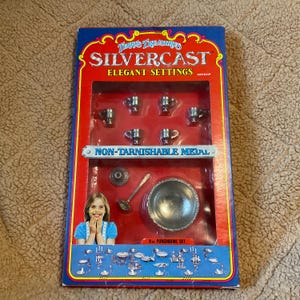May include: A red and white box with the words "Terry's Treasures Silvercast Elegant Settings" on the front. The box contains a set of miniature silver-plated cups, a punch bowl, a ladle, and a plate. The box also includes the text "Non-Tarnishable Metal" and "8 pc. Punchbowl Set".