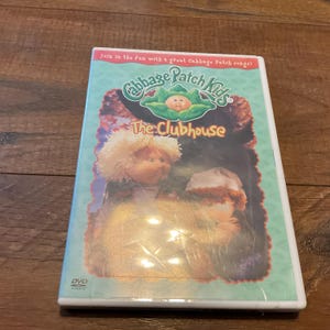 May include: A DVD case for "Cabbage Patch Kids: The Clubhouse." The cover features the Cabbage Patch Kids logo, the title, and illustrations of the characters. The case is in a plastic sleeve.