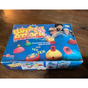 May include: A vintage "Whack Attack" board game box. The box is blue with the game title in large, yellow and red letters. The game features colorful, dome-shaped pieces and the text "The smash hit race against time!"
