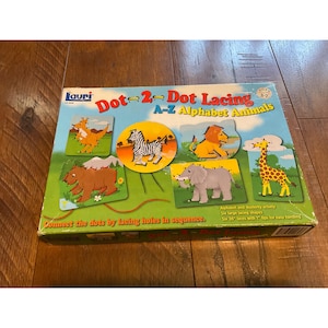 May include: A colorful box for a children's lacing activity. The box features a picture of six different animals, including a giraffe, elephant, zebra, lion, bear, and kangaroo. The box says "Dot-2-Dot Lacing A-Z Alphabet Animals" and "Connect the dots by lacing holes in sequence."