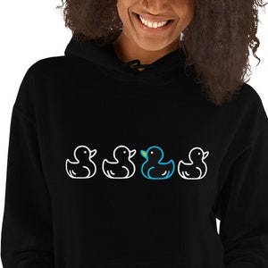 May include: Black hooded sweatshirt with a front pocket. The sweatshirt features a line of four cartoon duck illustrations, three white and one blue, across the chest. The ducks are outlined in white.