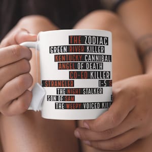 May include: White ceramic mug with black text listing the names of famous serial killers, including "The Zodiac", "Green River Killer", "Kentucky Cannibal", "Angel of Death", "Co-Ed Killer", "Strangler", "1-5-5", "The Night Stalker", "Son of Sam", and "The Weepy Voiced Killer".