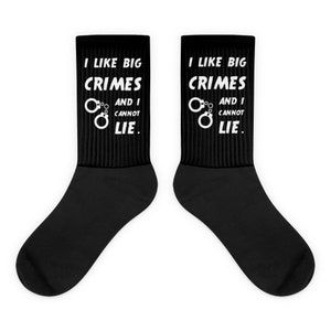 May include: A pair of black socks with white text that reads "I like big crimes and I cannot lie." The text is accompanied by a graphic of handcuffs.