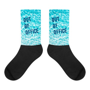 May include: A pair of black and blue socks with a blue and white water pattern and the text "OUT OF OFFICE" on each sock.