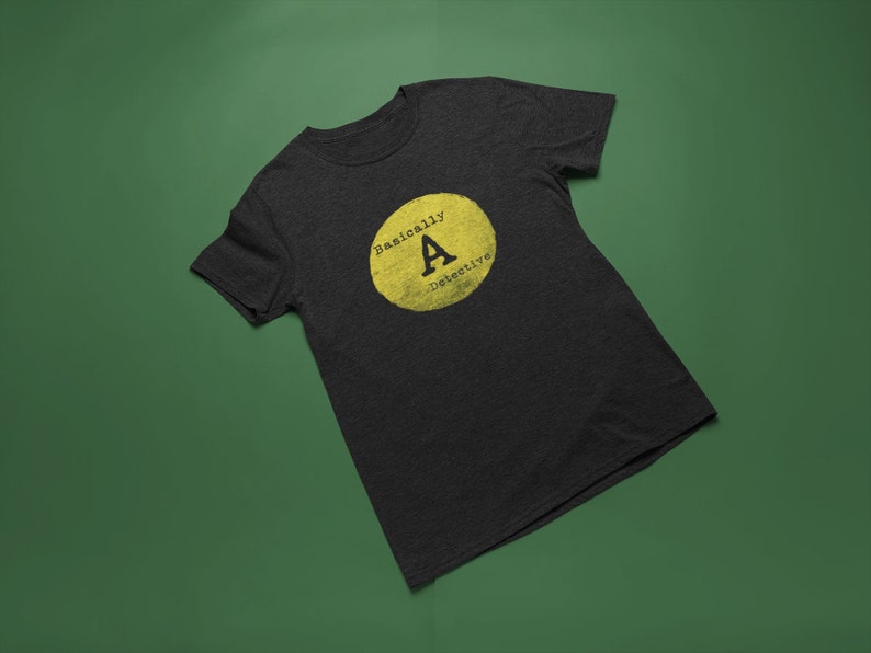 May include: A dark heather grey t-shirt with a yellow circle graphic that says "Basically A-OK" in black text.