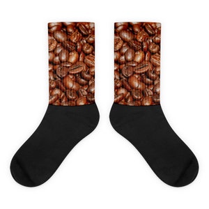 May include: A pair of black socks with a coffee bean design. The upper portion of each sock features a close-up image of roasted coffee beans in shades of brown. The foot portion of the socks is solid black.
