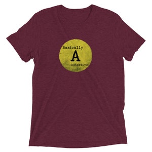May include: A maroon t-shirt with a yellow circle graphic that says "Basically A Detective" in black text.