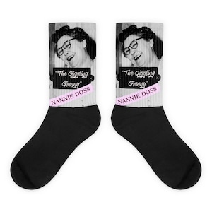 May include: Pair of black and white socks featuring a vintage black and white image of a woman wearing glasses. The text "The Giggling Granny" is above the name "Nannie Doss" in pink. The socks are a fun and unique accessory.