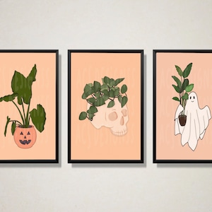 Może przedstawiać: Trzy oprawione wydruki w stylu Halloween. Każdy wydruk przedstawia roślinę w doniczce z innym pojemnikiem w stylu Halloween. Pierwszy wydruk przedstawia roślinę w doniczce w kształcie dyni. Drugi wydruk przedstawia roślinę w doniczce w kształcie czaszki. Trzeci wydruk przedstawia roślinę w doniczce w kształcie ducha.