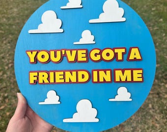 May include: A round blue wooden sign with white clouds and the text "You've Got A Friend In Me" in yellow and red letters.