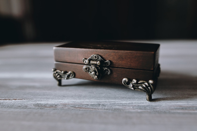 A small wooden box with a brown finish and ornate metal hinges and feet.