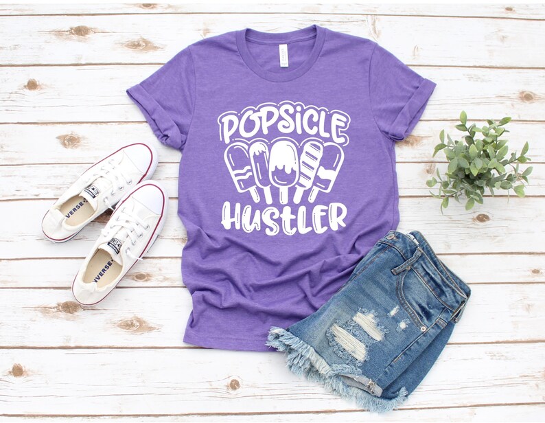 May include: Purple t-shirt with white text that reads "Popsicle Hustler" and a graphic of popsicles.