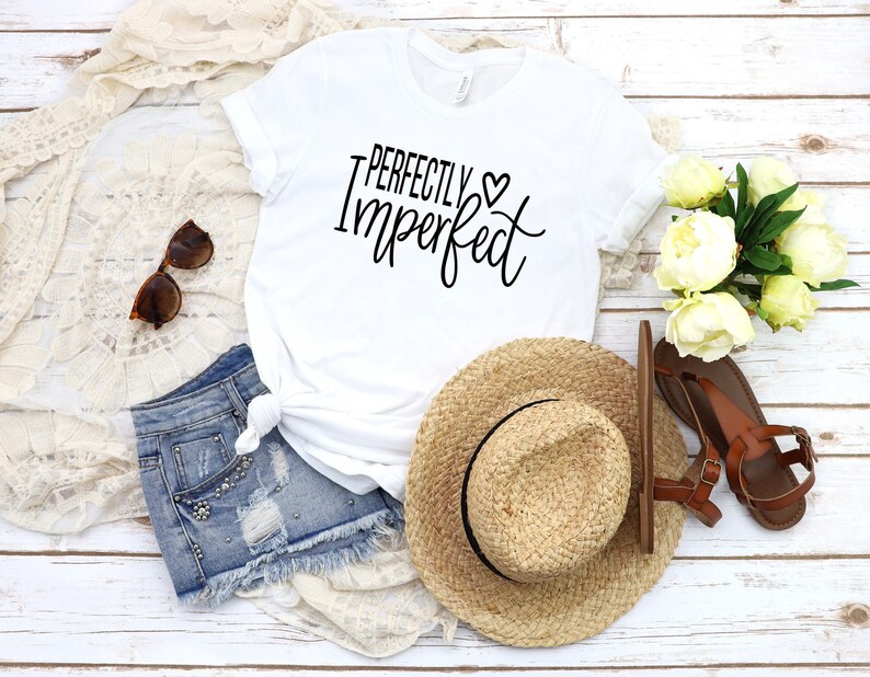 Puede incluir: Camiseta blanca con el texto "Perfectly Imperfect" en letras negras con un peque&ntilde;o s&iacute;mbolo de coraz&oacute;n.