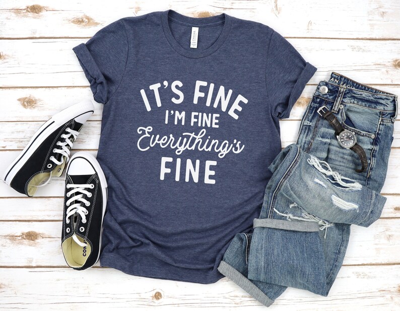 May include: A navy blue t-shirt with the text "It's Fine I'm Fine Everything's Fine" in white lettering.